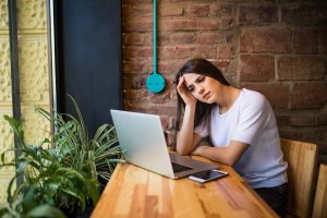 Woman holding computer, laptop tablet screen looking overwhelmed