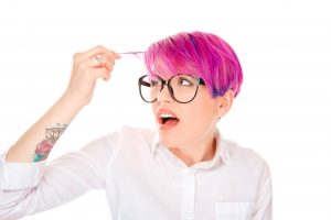 woman looking worried at her pink magenta color hair. 