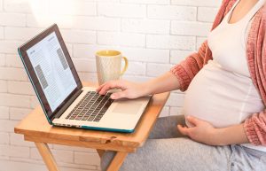 Pregnant woman on laptop at home