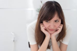 women sitting impatiently on toilet