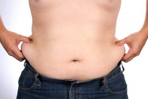man pinches the excess fat that he has around his waist.