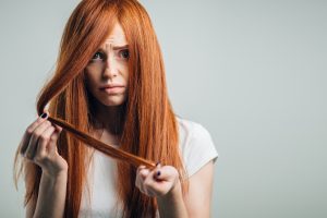 Sad redhead girl holding her hair