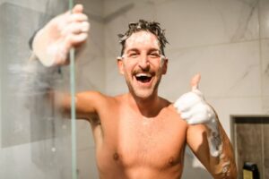 An adult male washing his hair in the shower