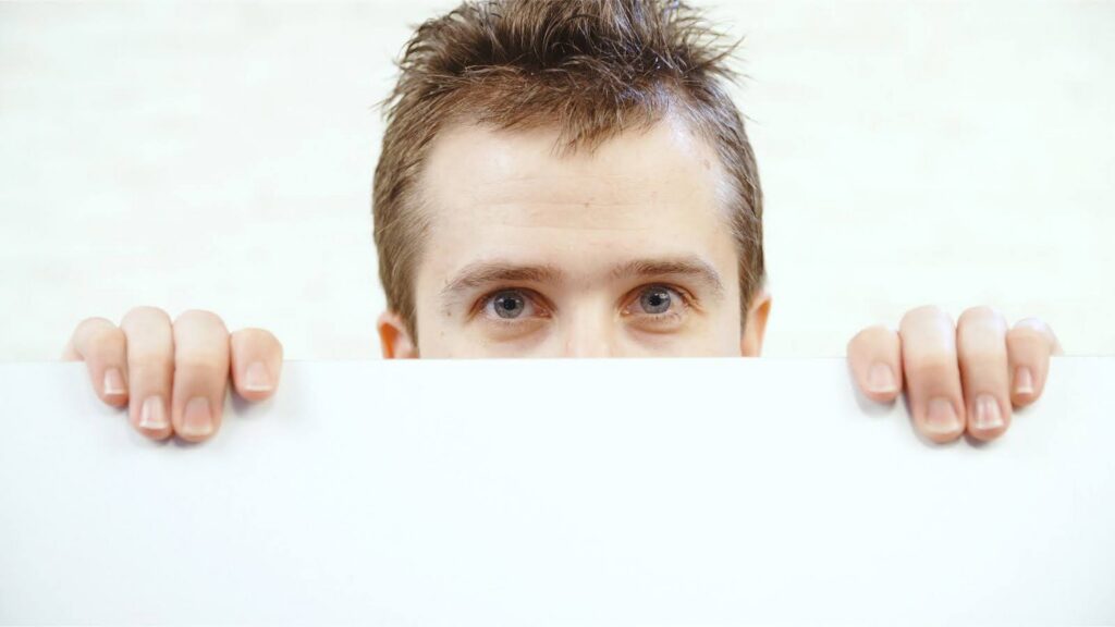 A man watching you over the top of a wall or door