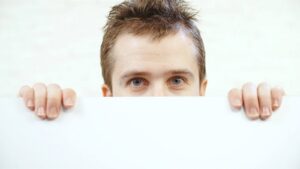 A man watching you over the top of a wall or door