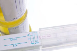 Urine drug test kit and sample cup showing temperature strip used to check urine temperature for drug test within the accepted testing range