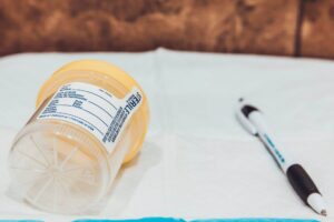 urine collection cup for a probation drug test next to a pen