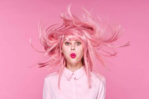 A young woman with pink hair against a dark pink background